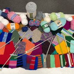 A large pile of donated wool, needles and knitted peggy squares