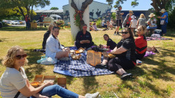 A group of people sitting on the grass, celebrating IVD2024