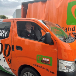 A man in the drivers' seat of the orange 0800 Hungry truck