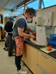 Two men wearing aprons in a commercial kitchen, preparing food