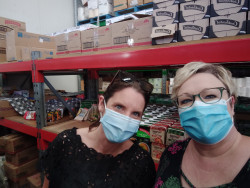 Two women standing in front of large shelves full of food and groceries items