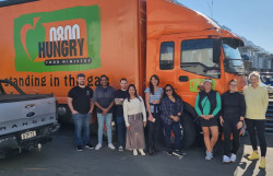 Staff from Spark standing in front of the large, orange 0800 Hungry delivery truck