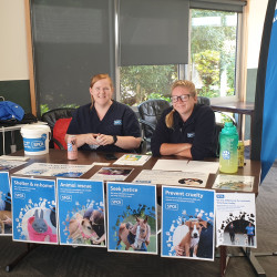 Two women from SPCA sit at a table displaying SPCA brochures and information