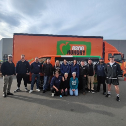 A large team of staff from Lion Beverages, standing in front of the orange 0800 Hungry truck