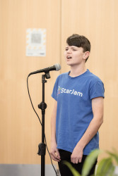 A boy stands and sings into a microphone