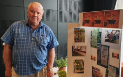 A man stands beside a display for The Just Dirt Trust