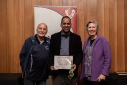 Sanjeewa Thanushka and two supporters, with his Award, in front of the Volunteering Canterbury banner