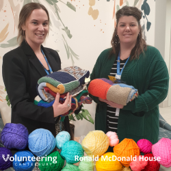 Two staff members from Ronald McDonald House with piles of Knit for Purpose blankets