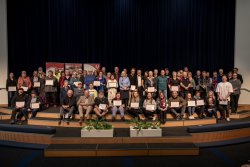 2025 Award recipients standing together on the stage with their certificates