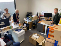 VolCan staff members Tammy, Mary-Ellen and Alison standing in an office surrounded by boxes