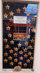 A floor to ceiling window with the Volunteering Canterbury logo in the centre. A sign says "Volunteer Recognition Awards 2022. Celebrating our volunteer 'stars'". The window is dotted with star shapes, within which are the photos of the 2022 Award recipients