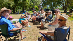 A group of people sitting in a park, celebrating IVD2024