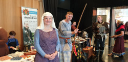 People in medieval dress, standing in front of a table