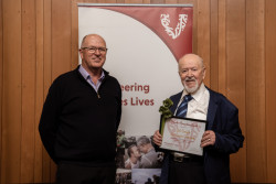 Zoli Somlyai and a supporter, with his Award, in front of the Volunteering Canterbury banner