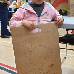 A young child holding a decorated brown paper bag