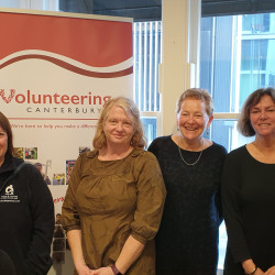 Seven people standing in front of a Volunteering Canterbury banner. VNZ Chief Executive Michelle Kitney in the centre, surrounded by VolCan staff, board members, and representatives from member organisations