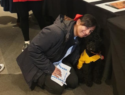 A woman kneels down to hug a dog