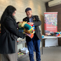 Councillor Mark Peters presenting a bundle of blankets to Katie Faithful, from Age Concern Canterbury