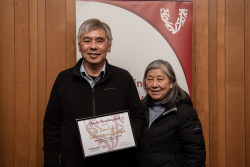 Simon Loi and a supporter, with his Award, in front of the Volunteering Canterbury banner