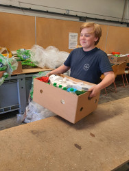 A student lifts a box filled with grocery items