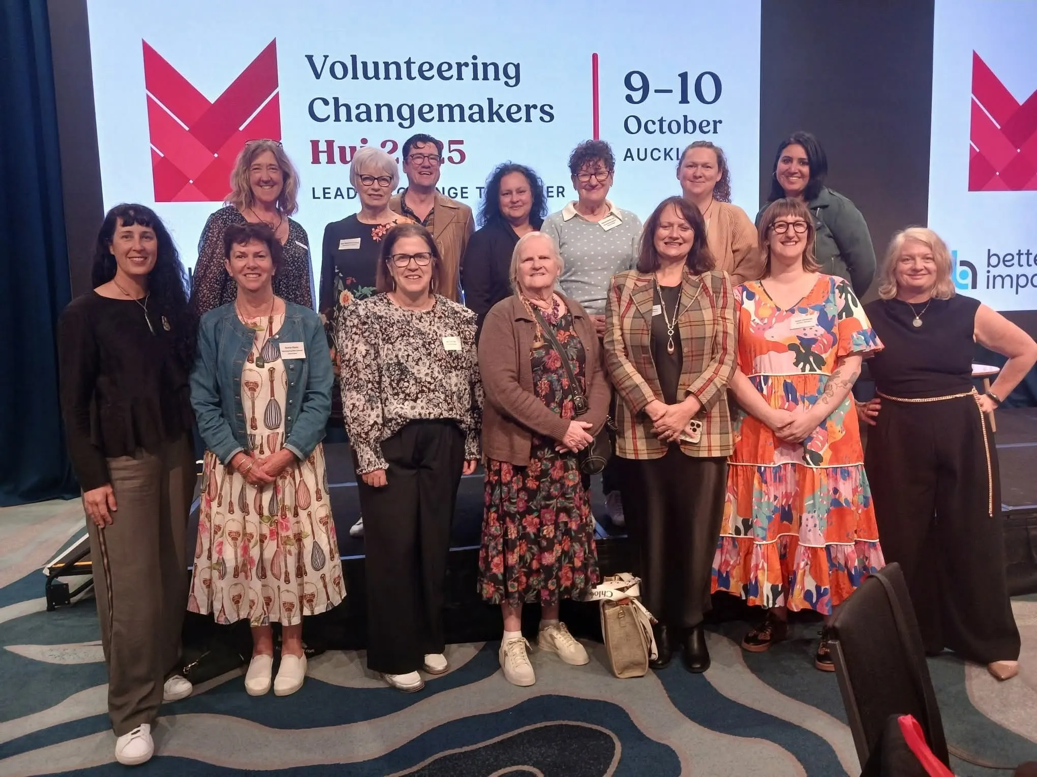 Representatives from Volunteer Centres around NZ, standing together in front of the stage screen